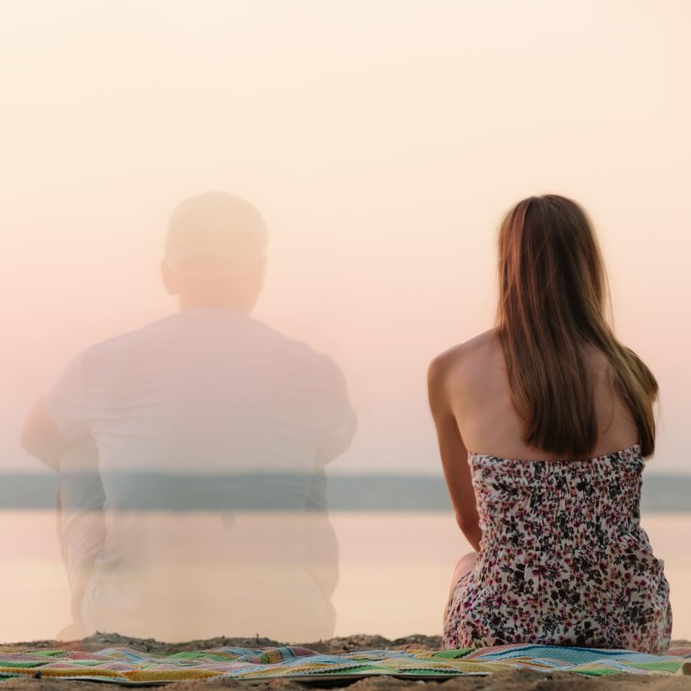 גבר חצי שקוף ובחורה יושבים על חוף הים