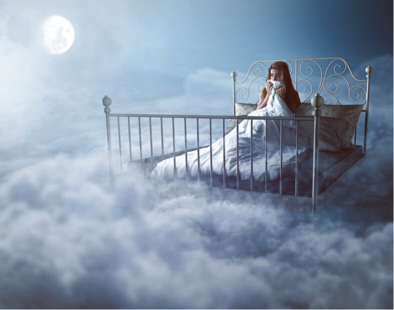 בחורה צעירה שוכבת במיטה בחלל אפוף עשן
