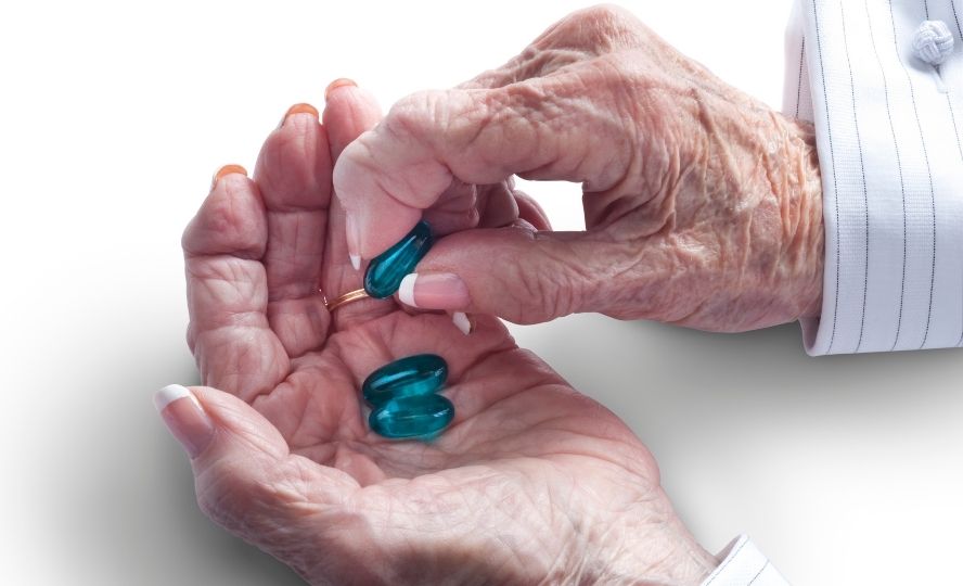 ידיים של קשישה האוחזת בתרופות - בדידות פוגעת במערכת החיסון