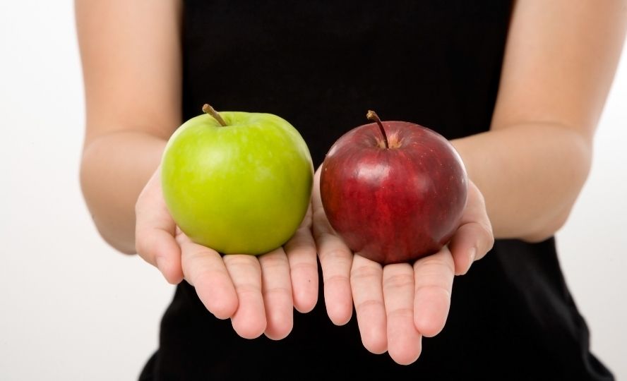 אישה מחזיקה תפוח ירוק ותפוח אדום