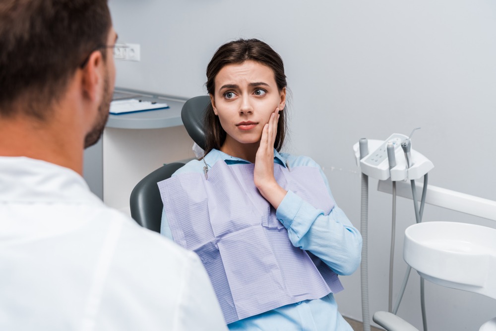 רופא שיניים מתשאל מטופלת עם כאבים