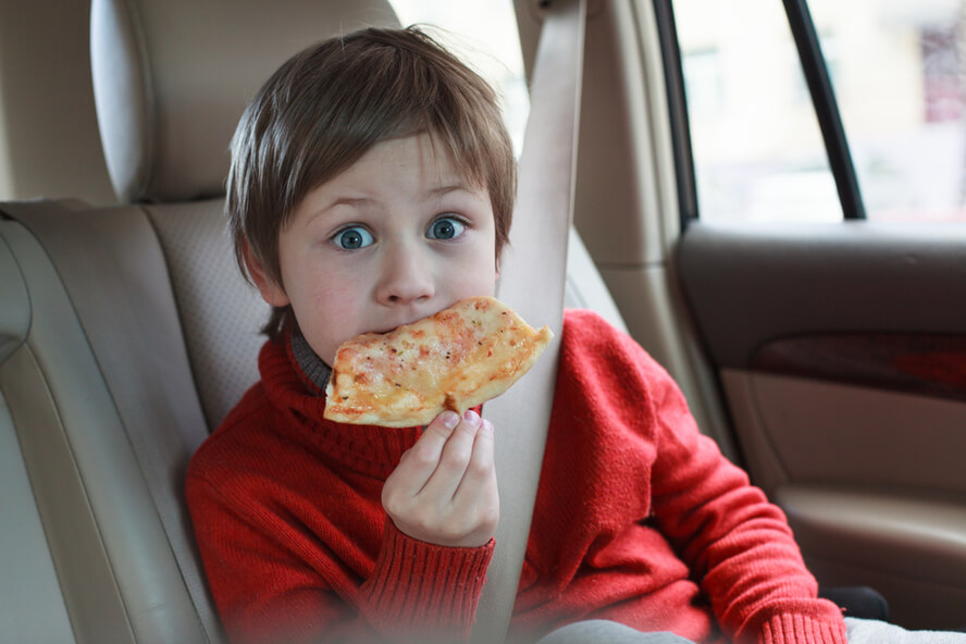ילד אוכל פיצה בזמן הנסיעה - בחילה מאוכל שומני 
