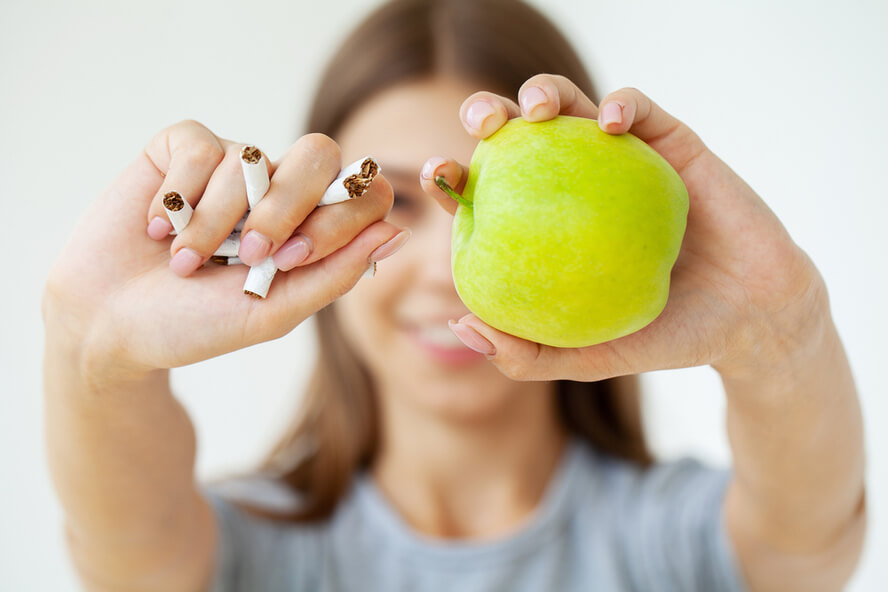 בחורה מחזיקה תפוח וסיגריות