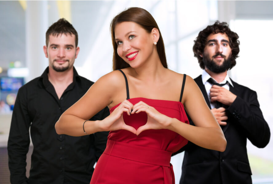 בחורה עומדת לפני שני גברים ומציגה סימן של לב - פוליאמוריה או זוגיות פתוחה