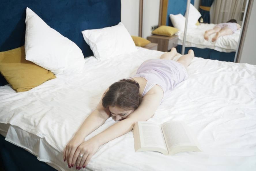 אישה שוכבת על המיטה עם ספר