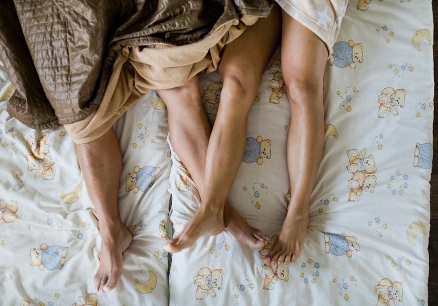 גבר ואישה ישנים תחת שמיכות במיטה