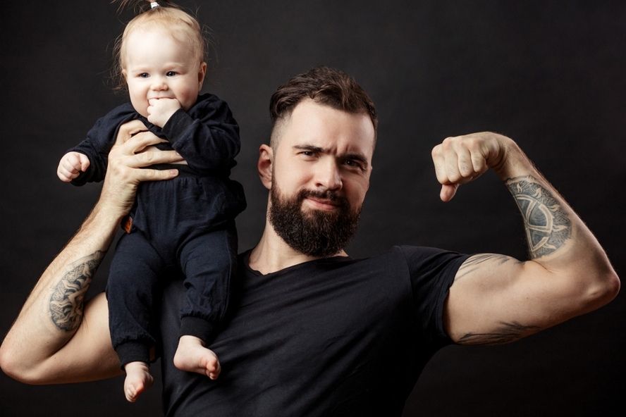 גבר שרירי מלא טסטוסטרון אוחז בתינוק