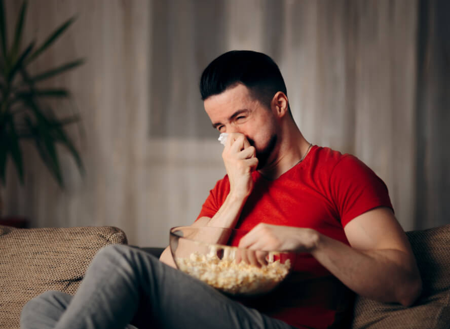 גבר בוכה מול הטלוויזיה ואוכל פופקורן - דמעות זולגות מול הטלוויזיה
