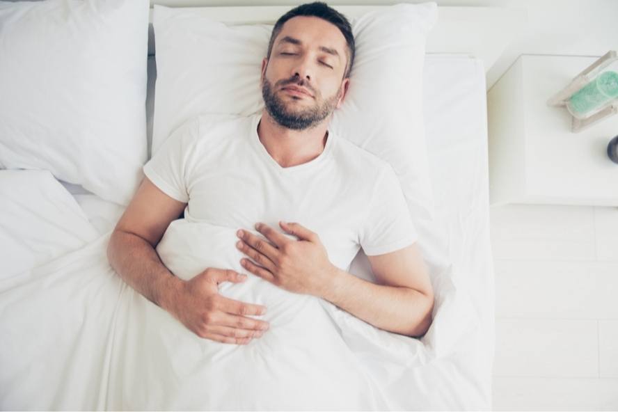 גבר שוכב במיטה - מבצע מדיטציית מיינדפולנס סריקת גוף