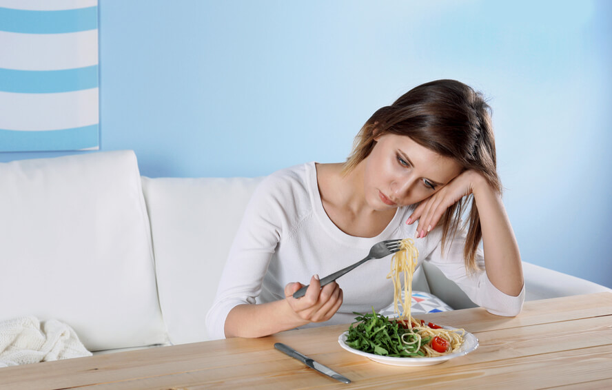 אישה חסרת אנרגיה מתעסקת בצלחת אוכל