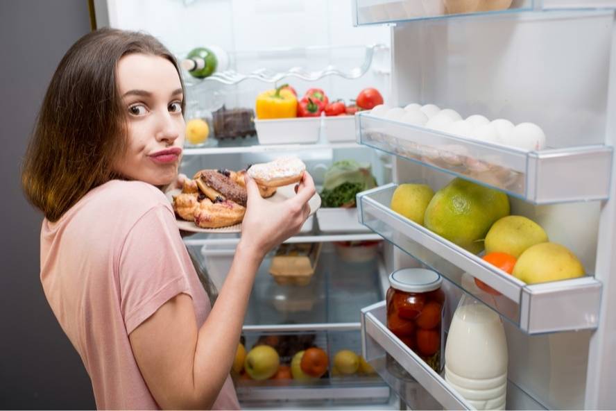 אישה אוכלת דונאטס ישר מהמקרר אכילה רגשית