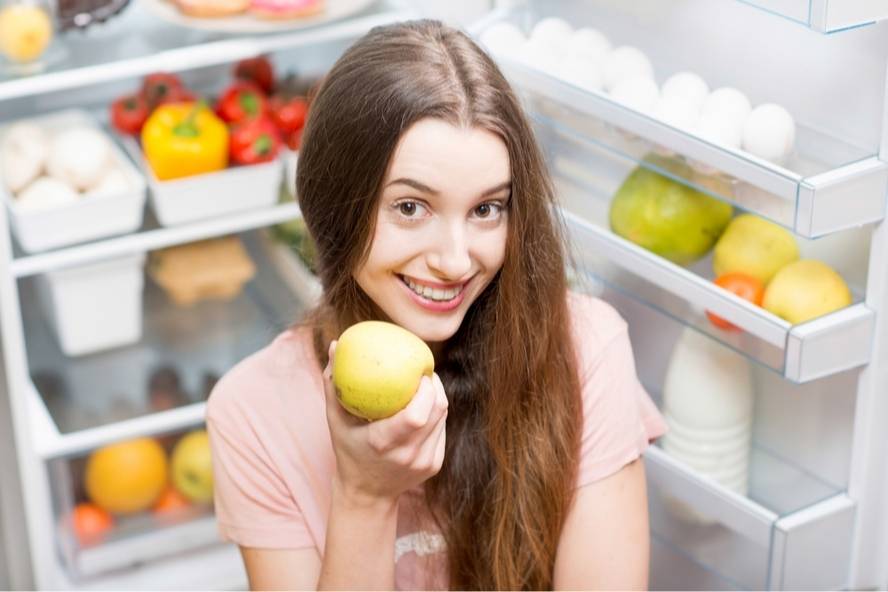בחורה מול המקרר אוכל תפוח
