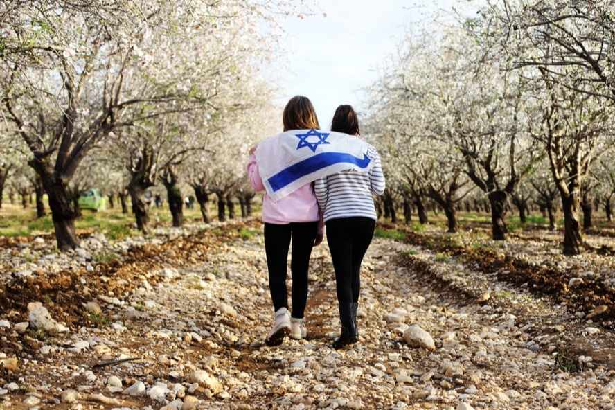 שתי נערות צועדות עם דגל ישראל על הגב