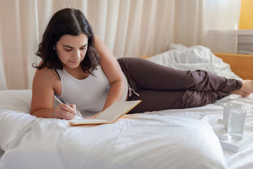 אישה כותבת ביומן על המיטה