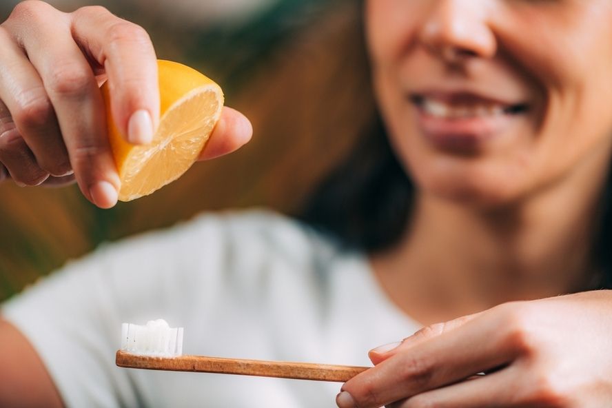 אישה מטפטפת מיץ לימון על מברשת שיניים - הלבנת שיניים ביתית