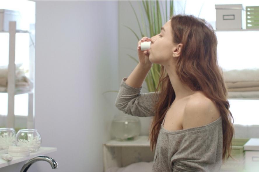 אישה שותה שמן קוקוס מכוסית - הלבנת שיניים טבעית