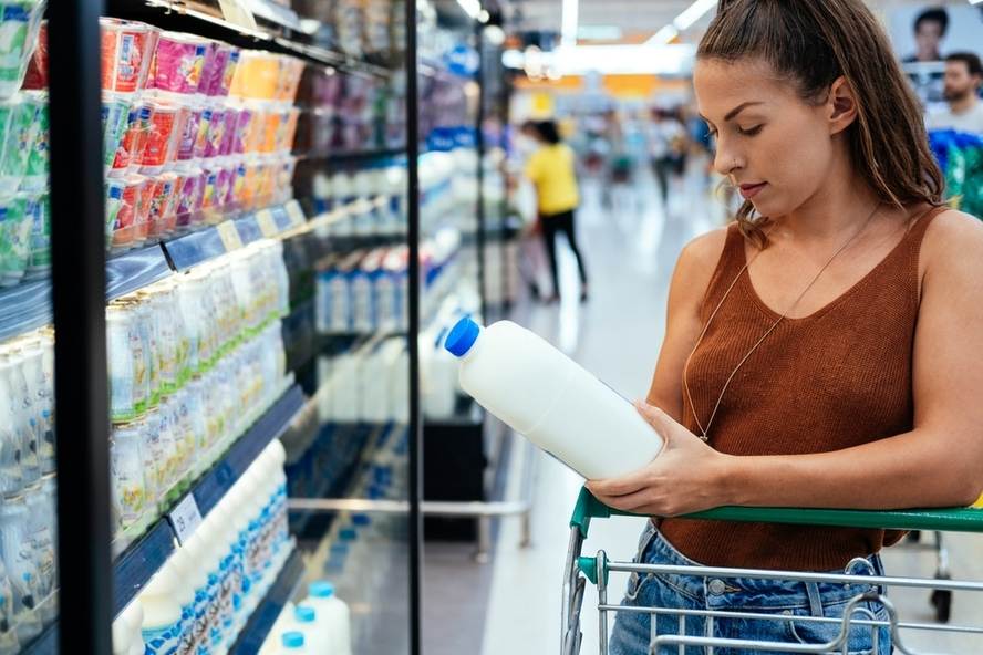 אישה בסופרמרקט בוחנת חלב דל לקטוז - חלב נטול לקטוז
