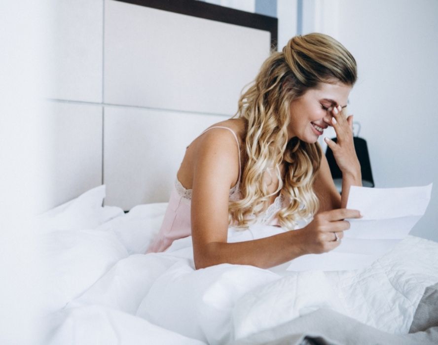 אישה קוראת מכתב אהבה במיטה