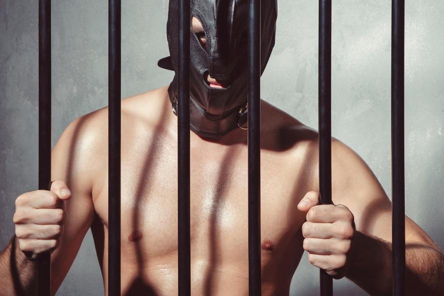 BDSM - גבר מאחורי הסורגים עם מסיכת עור קינקית 