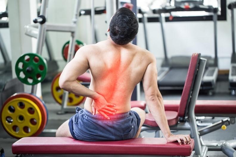גבר סובל מכאבי גב לאחר אימון משקולות