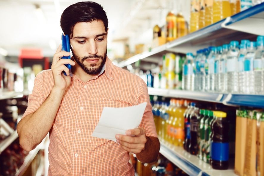 רשימת קניות לסופרמרקט: גבר עם רשימת קניות משוחח בטלפון בסופר