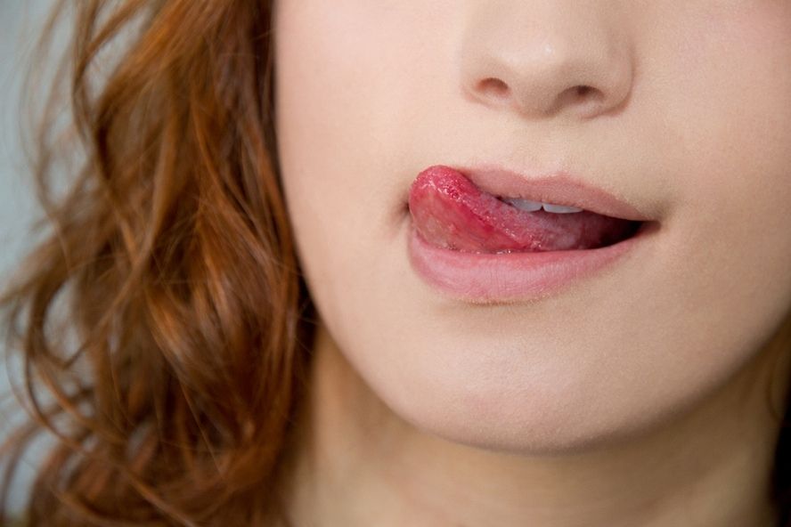 אישה עם שפתיים יבשות מלקקת את השפתיים