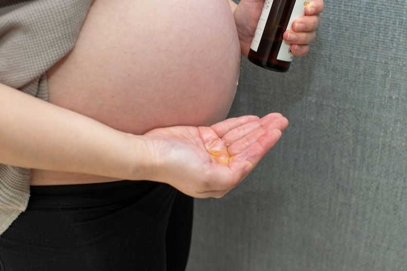 אישה בהיריון מורחת שמן קוקוס על הבטן על מנת להימנע מסימני מתיחה