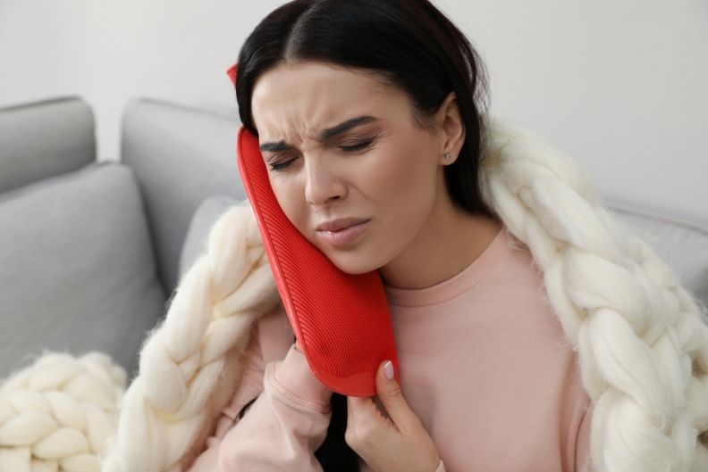 אישה משתמשת בבקבוק חם להקלה על כאבי אוזניים